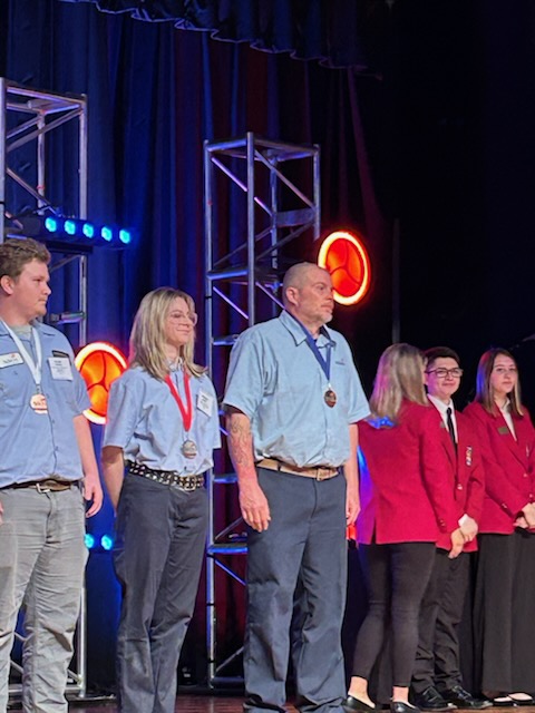 Peter Baldasoro on stage with blue medal